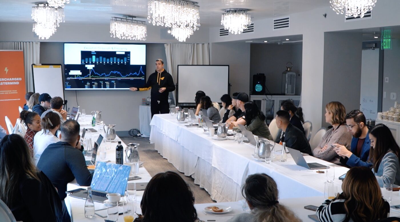 Drew Hitchcock presenting YouTube analytics to a room of creators at a mastermind